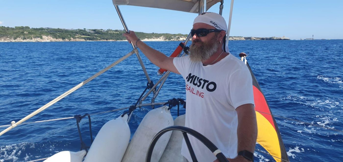 Skipper am Steuerrad einer Segelyacht vor der Küste